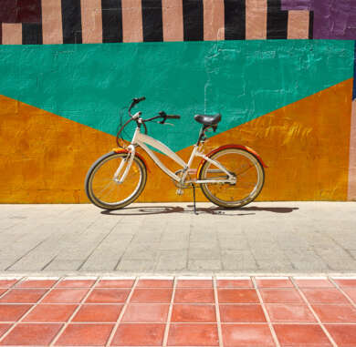Closeup shot of a bicycle parked near a colorful painted wall in the city